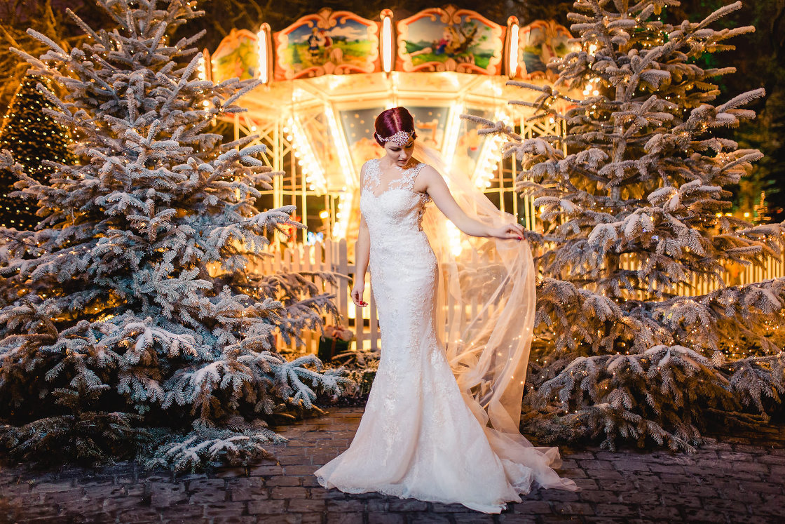 Braut im Brautkleid vor verschneiten Tannenbäumen im Europa Park